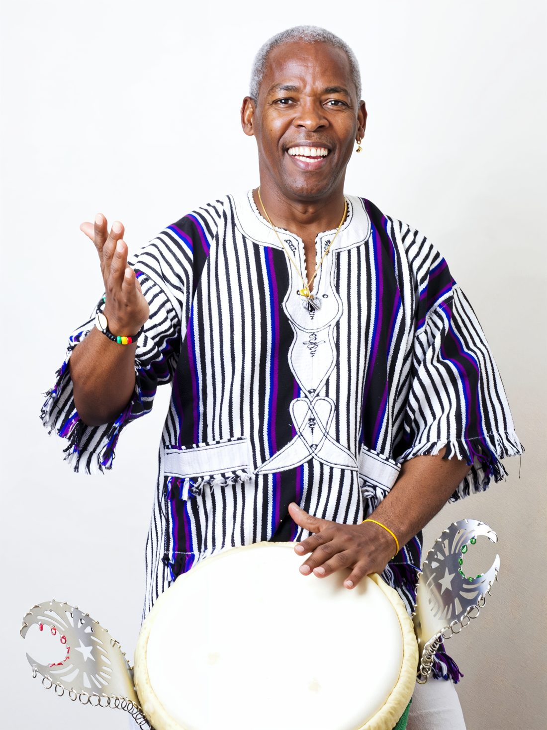 Percussionniste en boubou rayé derrière son djembé