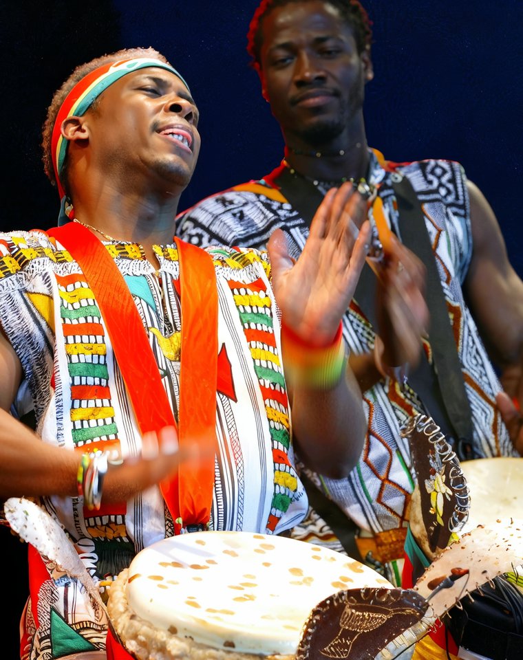 Deux percussionnistes en tenue traditionnelle sur scène, en pleine performance